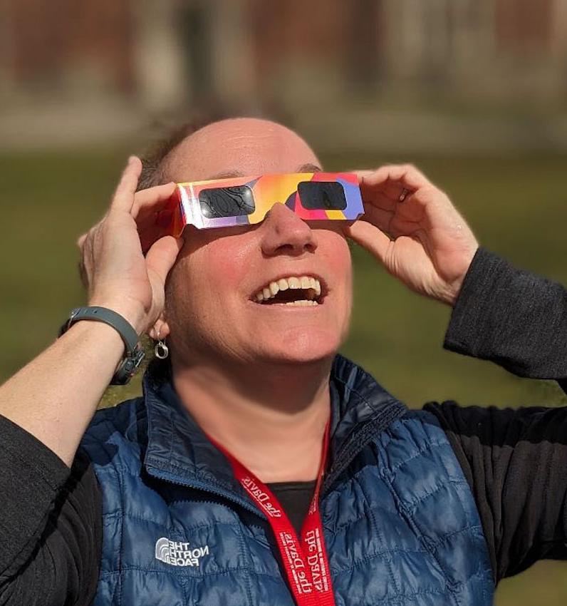 Headshot of Nell Gould wearing eclipse glasses